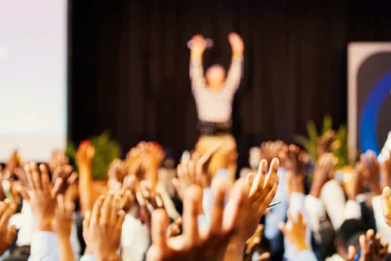People in the audience raising their hands at a business networking group.